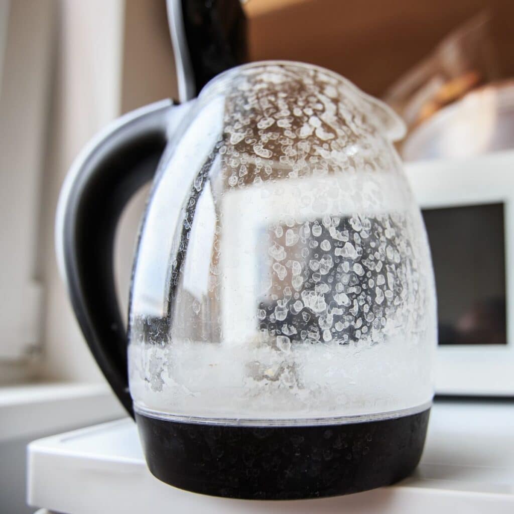 A glass electric kettle covered in mineral limescale deposits, a common subject in our frequently asked questions.