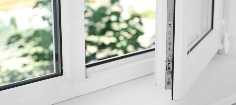 A white uPVC window frame with a metal locking mechanism visible on the open sash.